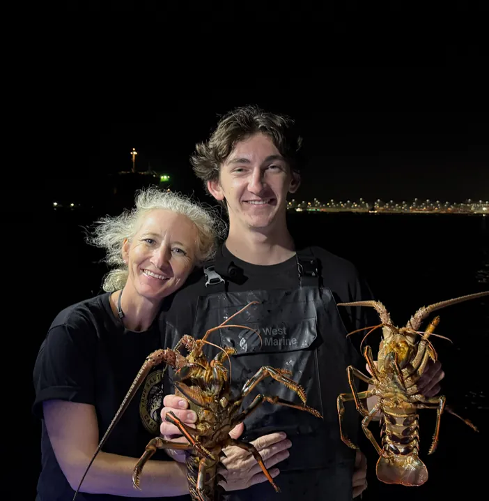 Tucker and Ericka holding spiny lobsters at night